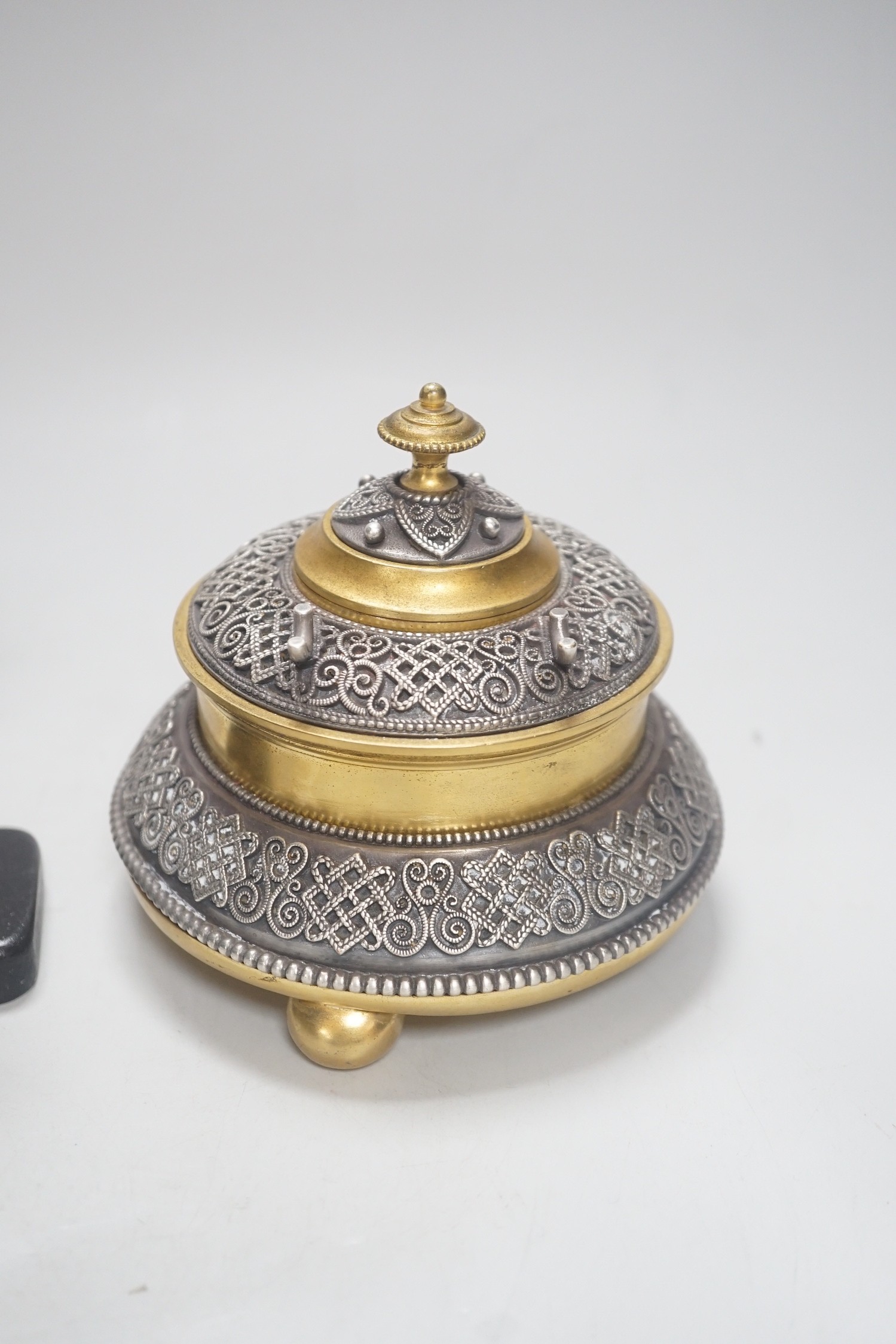 A Continental silvered and gilt metal inkwell, c.1900, and an Indo-Persian silvered bronze ‘fish’ tap or cane handle on stand, 16cm